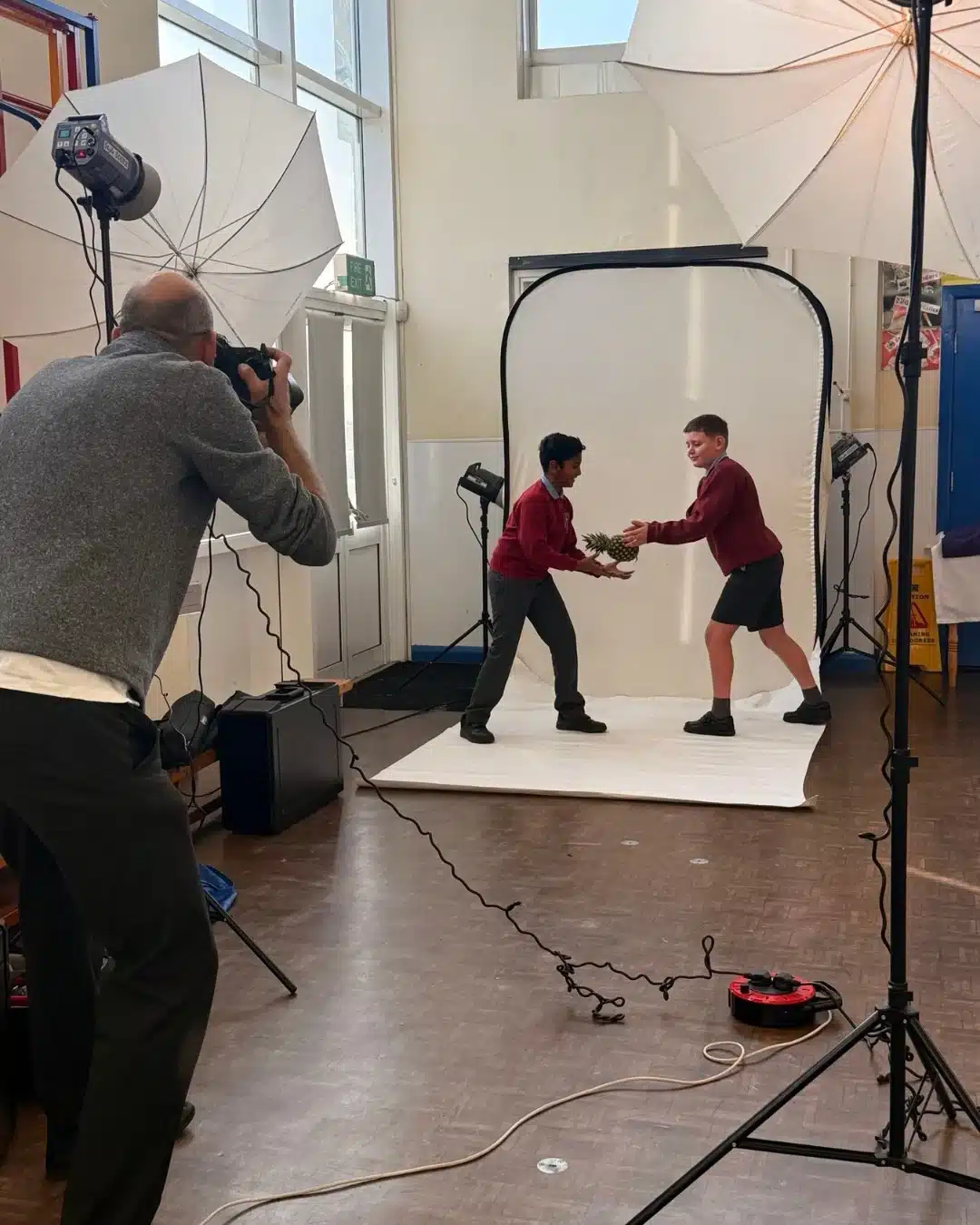 Photographer captures pupils passing a pineapple in studio