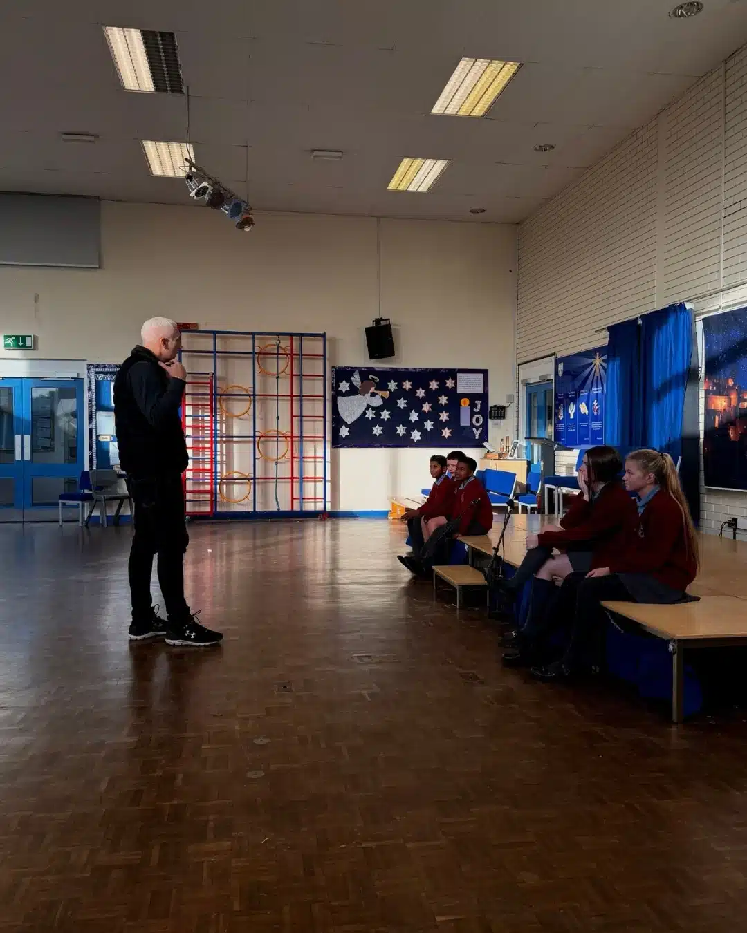 Presenter speaking to pupils in a school hall