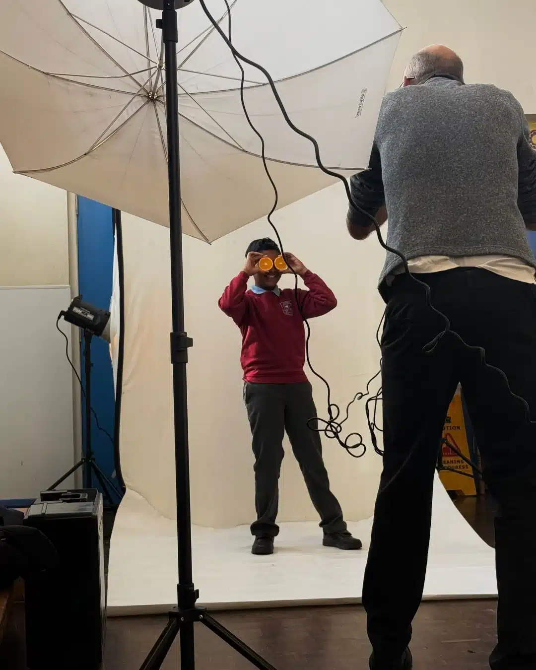 Child poses with orange slices during studio photoshoot